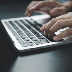 Nahaufnahme von Händen, die konzentriert auf einer Laptop-Tastatur arbeiten – Fokus auf digitale Dateneingabe.