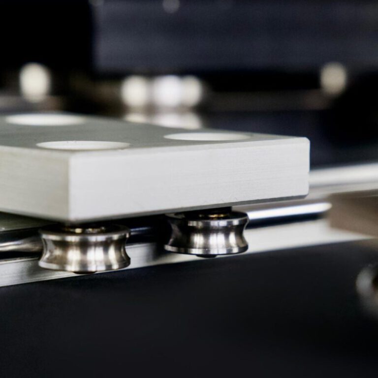 Detailaufnahme eines Linearführungssystems mit präzisionsgefertigten Laufrollen und Aluminium-Schlitten. Das Bild zeigt die glatte Oberfläche und die hochwertige Verarbeitung der mechanischen Komponenten für industrielle Anwendungen.